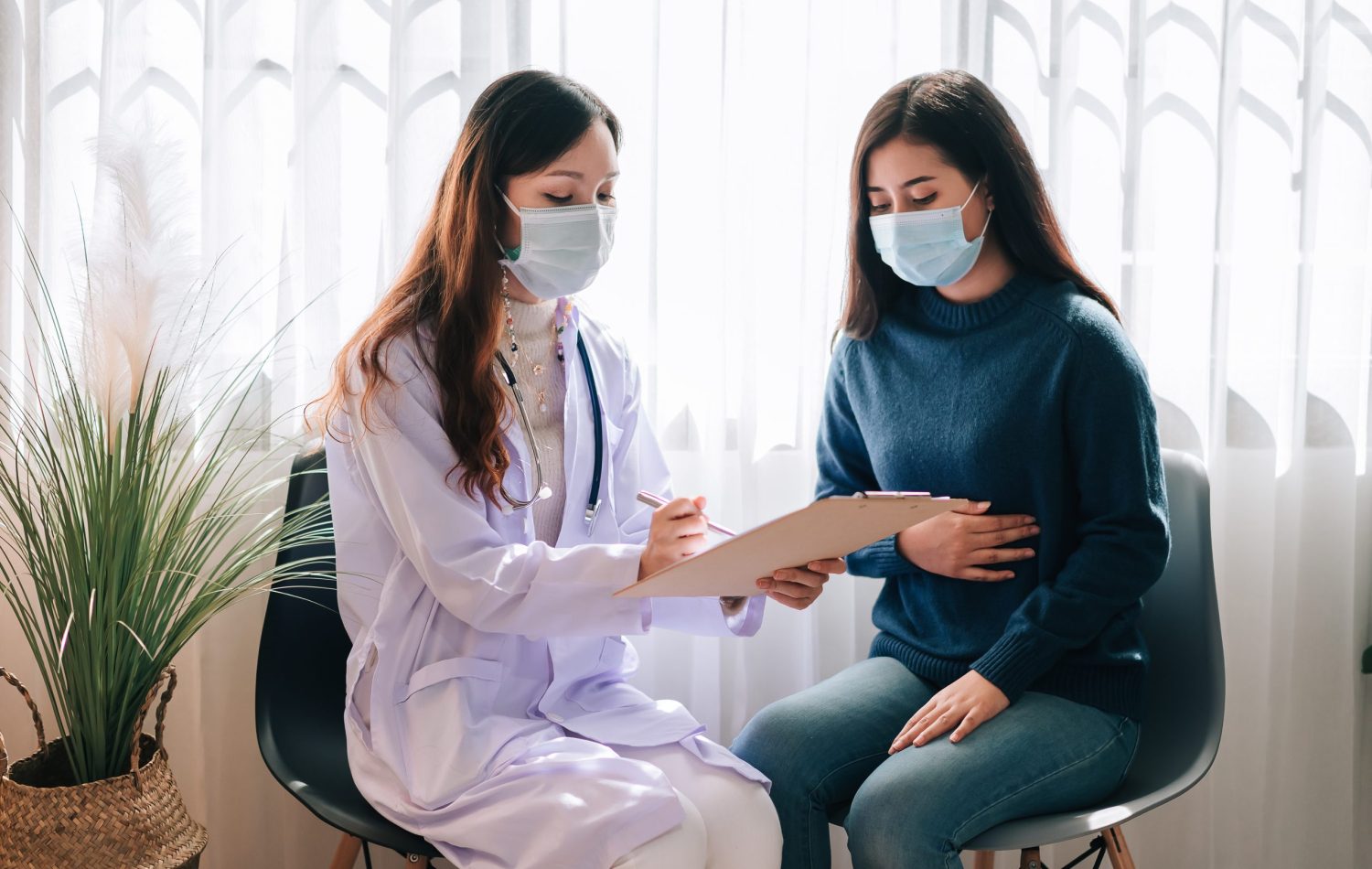 Female doctor talking to a lady holding her belly